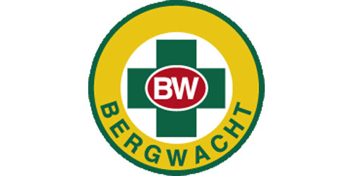 innen: grünes Kreuz mit den Buchstaben BW in der Mitte, außen: großer Kreis mit Aufschrift BERGWACHT 