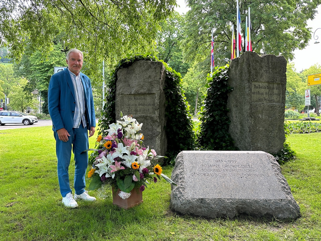 Ob Späth steht neben einem Blumenstrauß am Verfassungsplatz. 