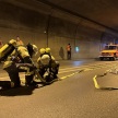 Zwei Feuerwehrmännner knien auf dem Boden im Tunnel und halten Löschschläuche in den Händen. 