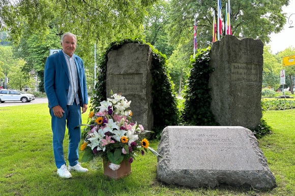 Ob Späth steht neben einem Blumenstrauß am Verfassungsplatz. 