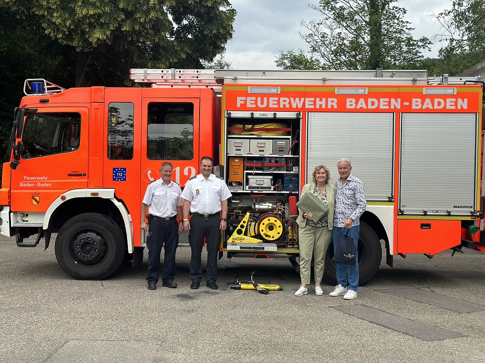 Vier Menschen stehen vor einem Feuerwehrfahrzeug mit der Aufschrift "Feuerwehr Baden-Baden"
